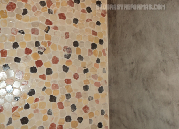 Microcemento en pared de ducha combinado con piedras de colores.